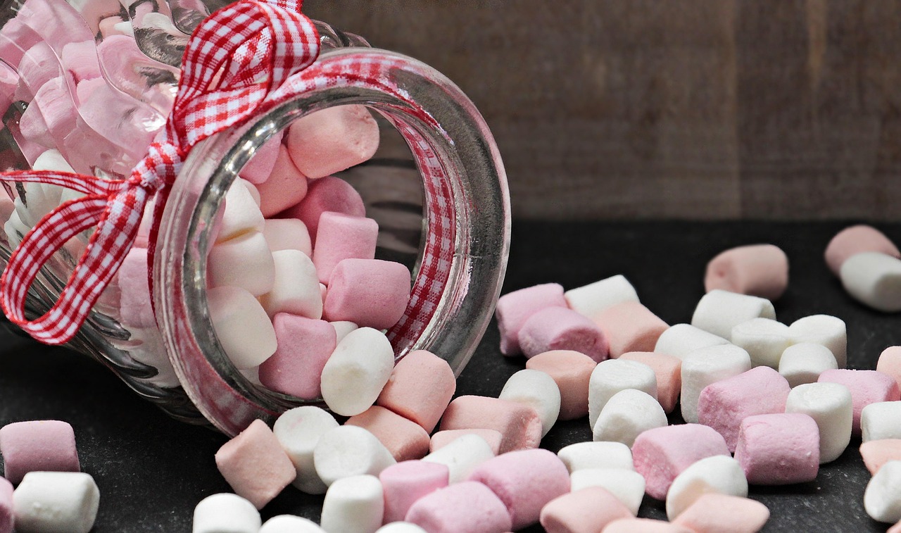 Bocal de guimauves roses et blanches renversé sur une table